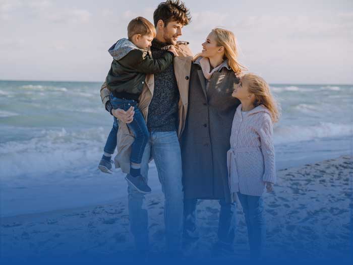 A father on a beach holding his wife and children, thinking he needs mortgage protection.