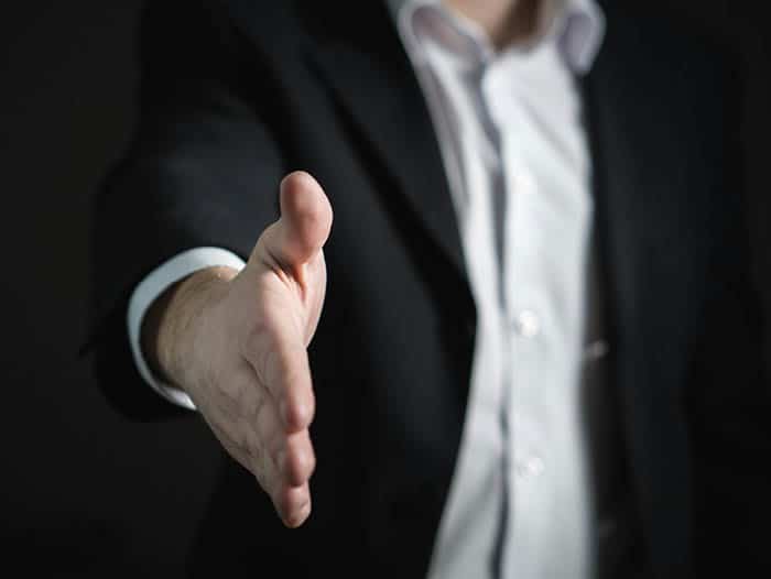 Man in suit offering his hand to shake for investment opportunity