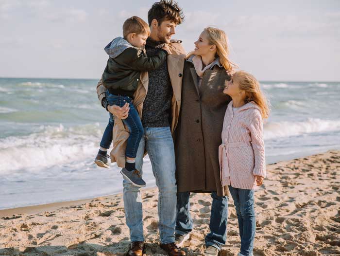 A father on a beach holding his wife and children, thinking he needs mortgage protection.